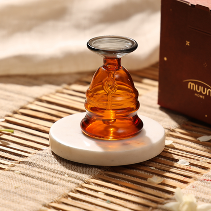 Amber glass puja bell on a marble coaster beside its gift box