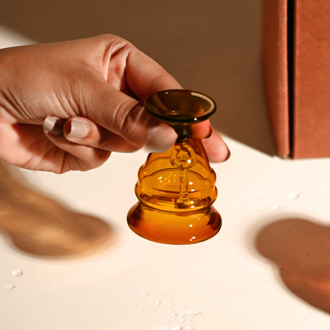 Amber glass bell held by its slate-grey handle