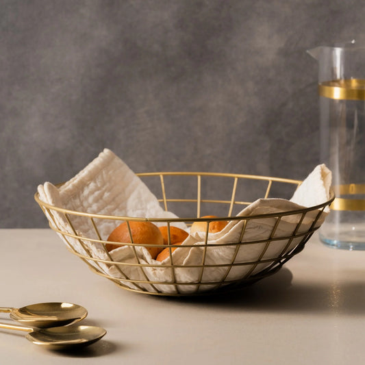 Gold wire bread basket lined with a napkin and filled with rolls