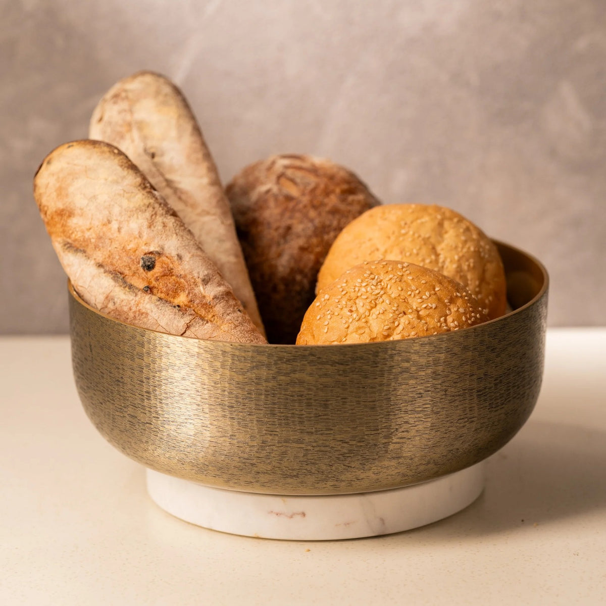 Hammered gold bowl with marble base filled with bread