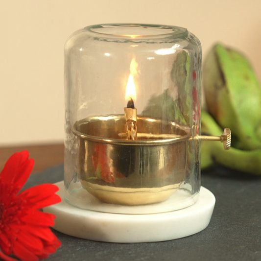 Brass Akhand Jyot diya with hammered glass cover on a marble base