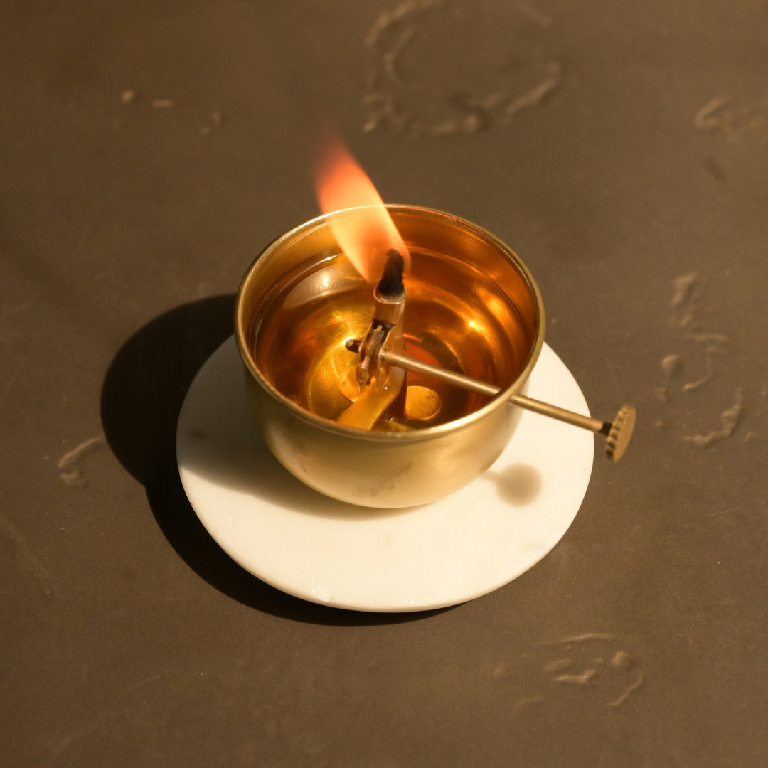 Brass diya on a Banswara marble base with a lit wick