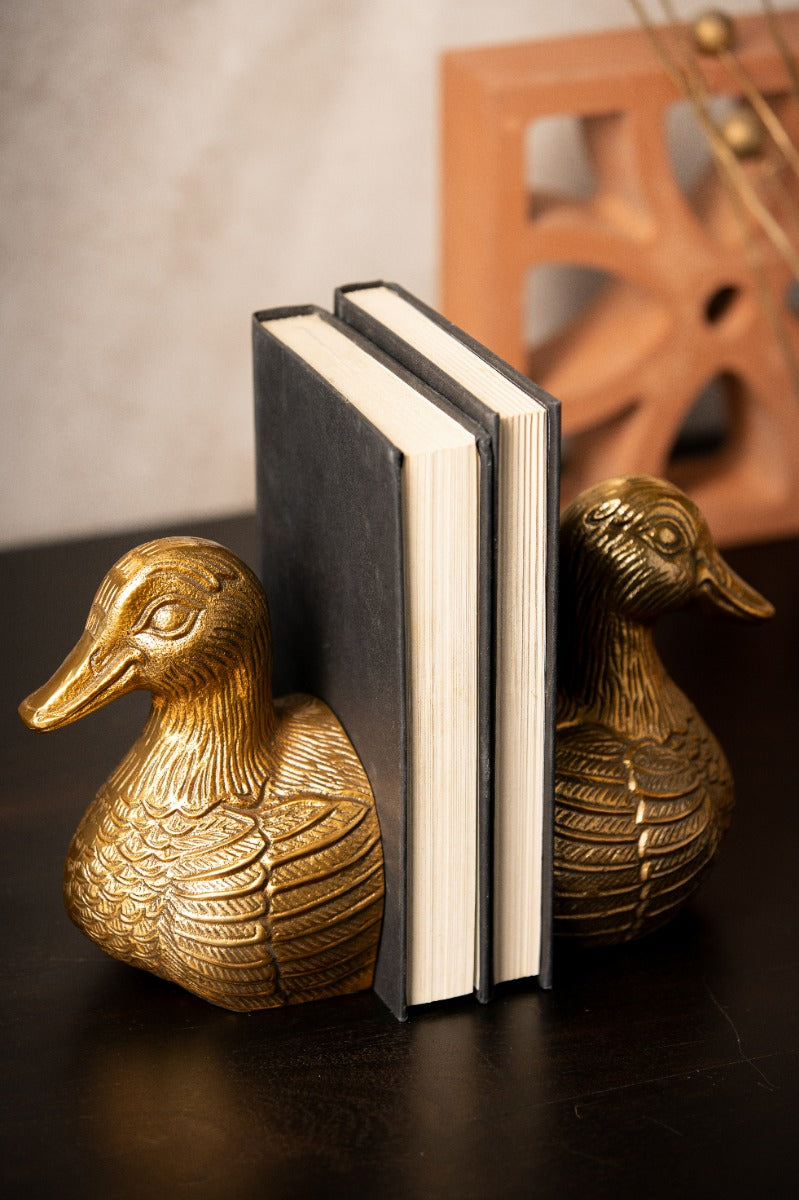 Pair of gold duck bookends on a dark shelf