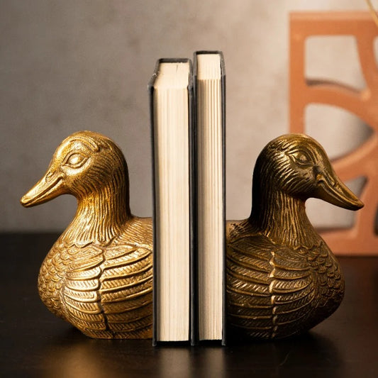 Antique gold duck bookends holding books