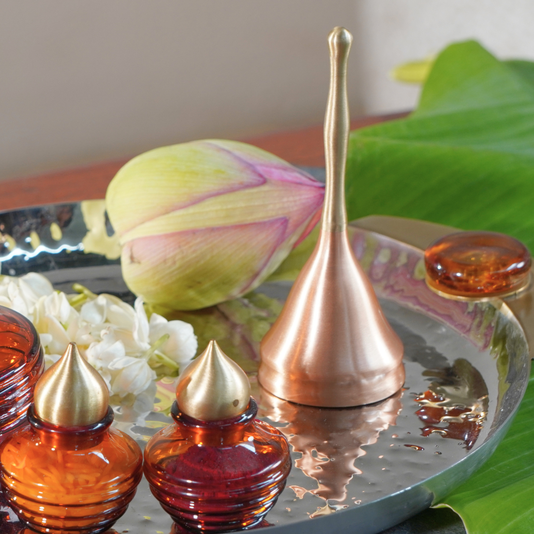 Brass and copper puja bell on a puja thali with lotus and flowers