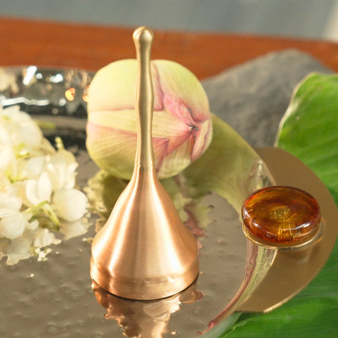 Sculptural brass and copper ghanti beside a lotus bud