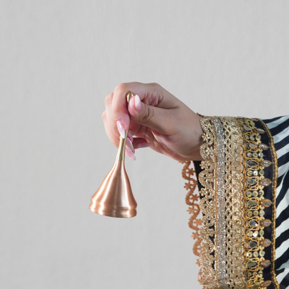 Brass and copper puja bell held in hand