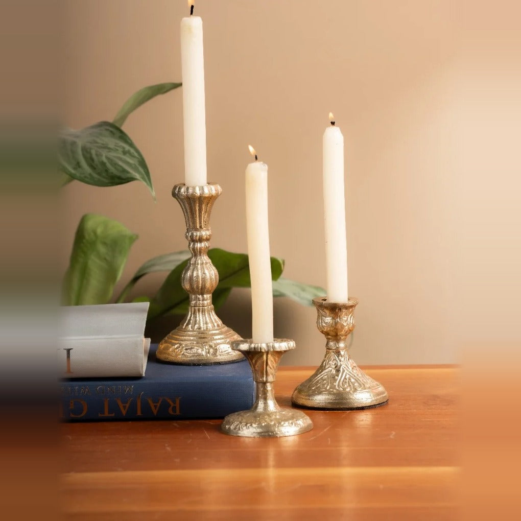 Three colonial taper candle holders with lit white candles
