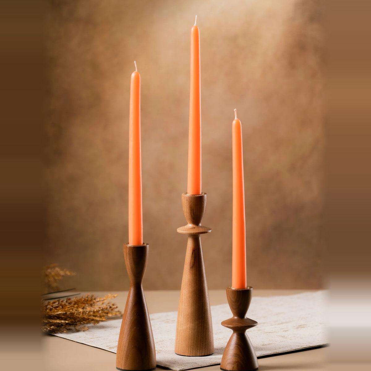 Three wooden candle holders with orange taper candles