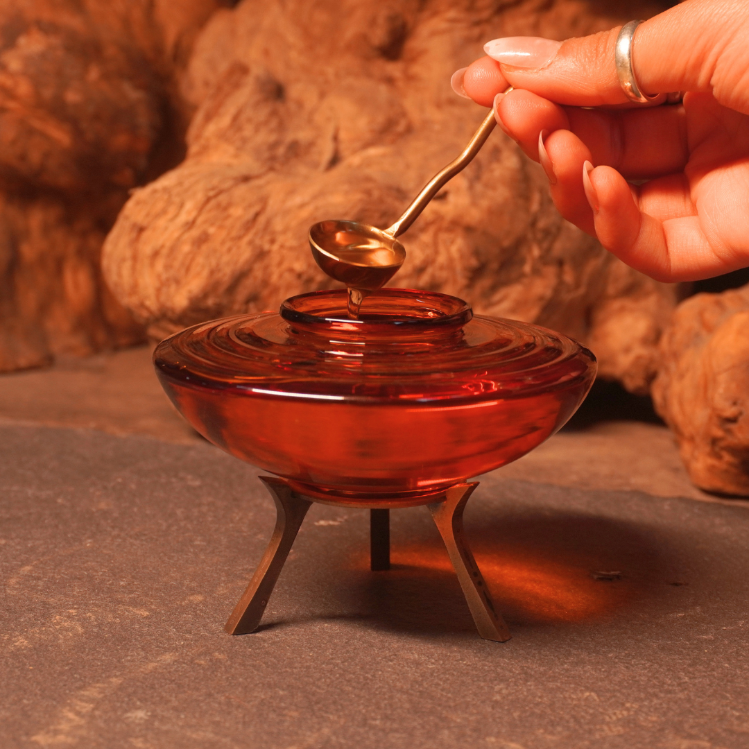 Spooning ghee from an amber glass ghee pot