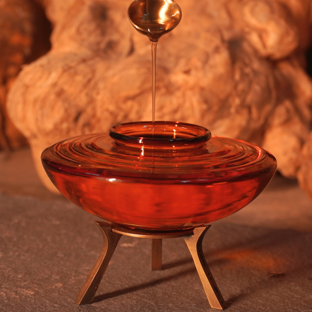 Warm ghee drizzling from a brass spoon