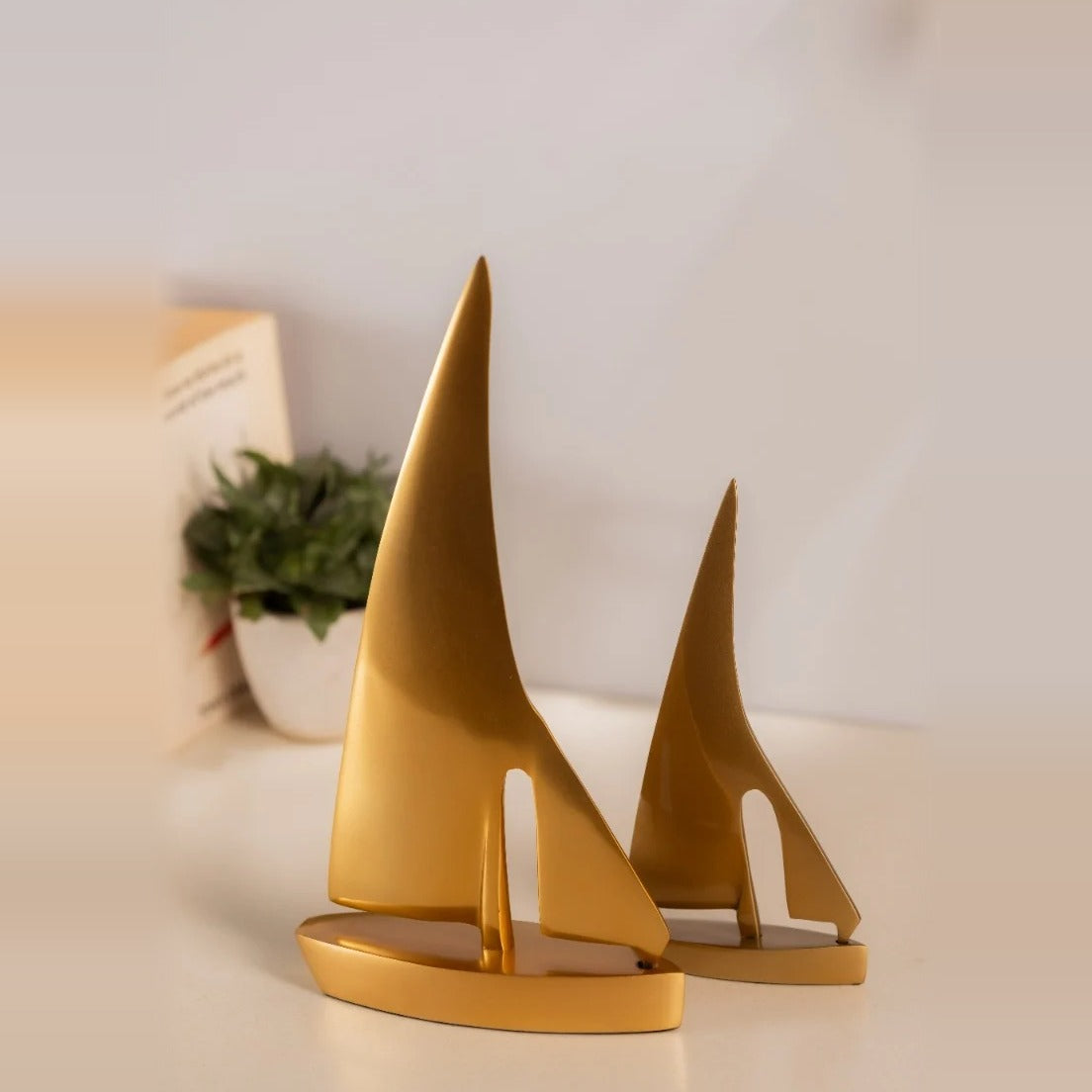Pair of golden sail boat sculptures on a shelf