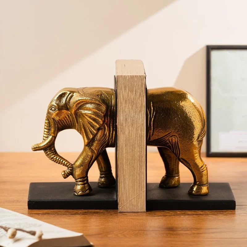 Gold elephant bookend holding books on a wooden desk