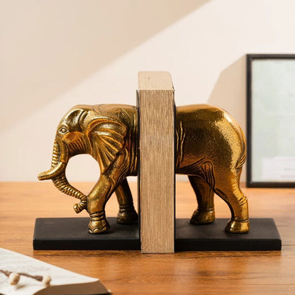 Gold elephant bookend holding books on a wooden desk