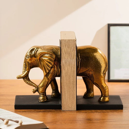 Gold elephant bookend holding books on a wooden desk