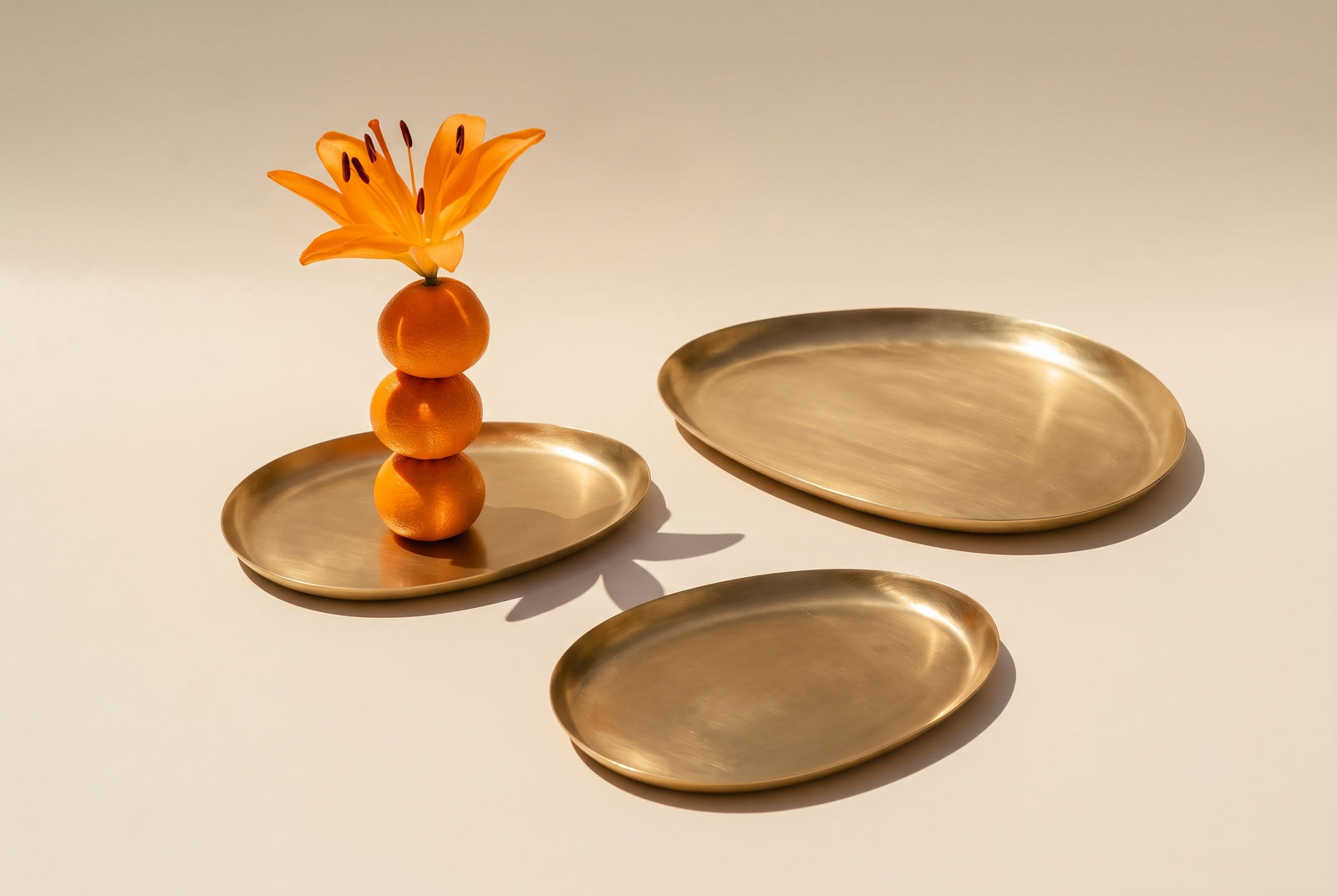 Brass serving trays styled with oranges and a lily