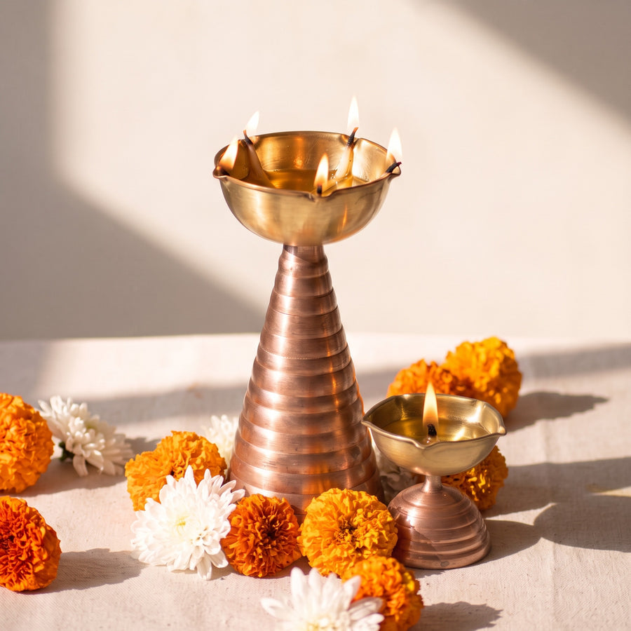 Brass and copper diyas lit among marigolds