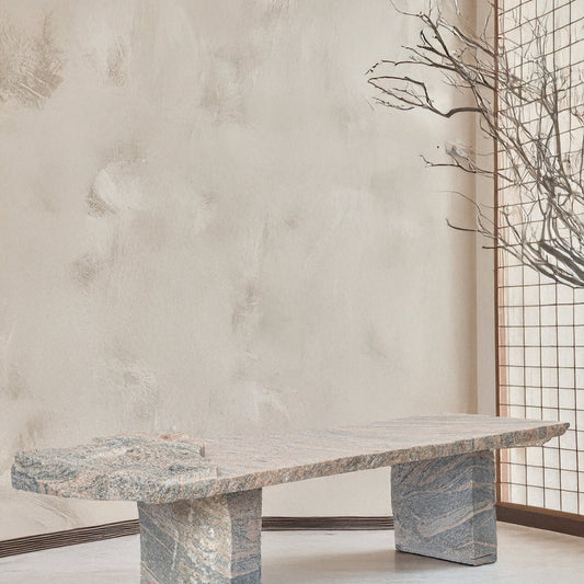 Marble dining table against a textured wall with a minimalistic interior design.
