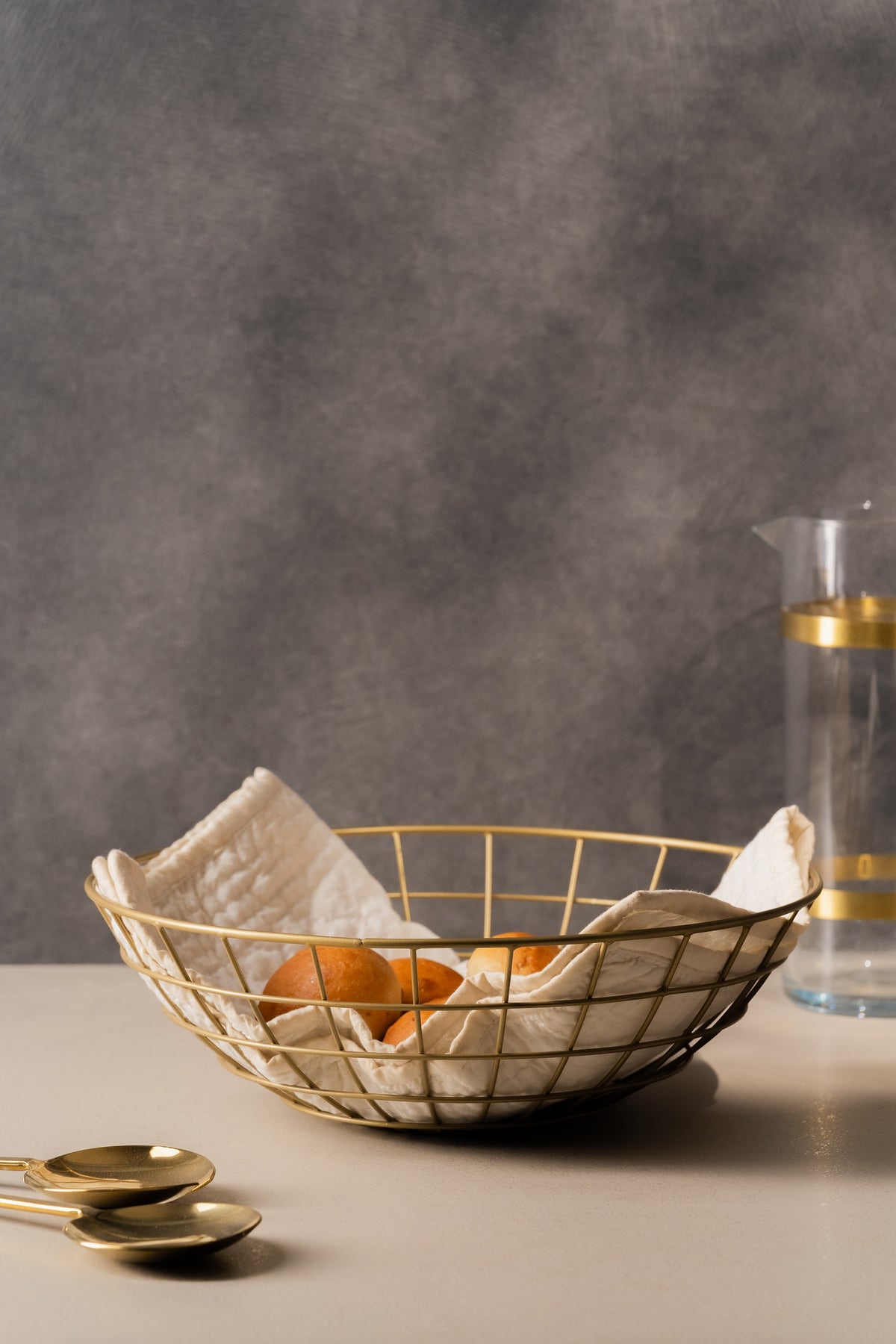 Gold wire bread basket lined with a napkin and filled with rolls