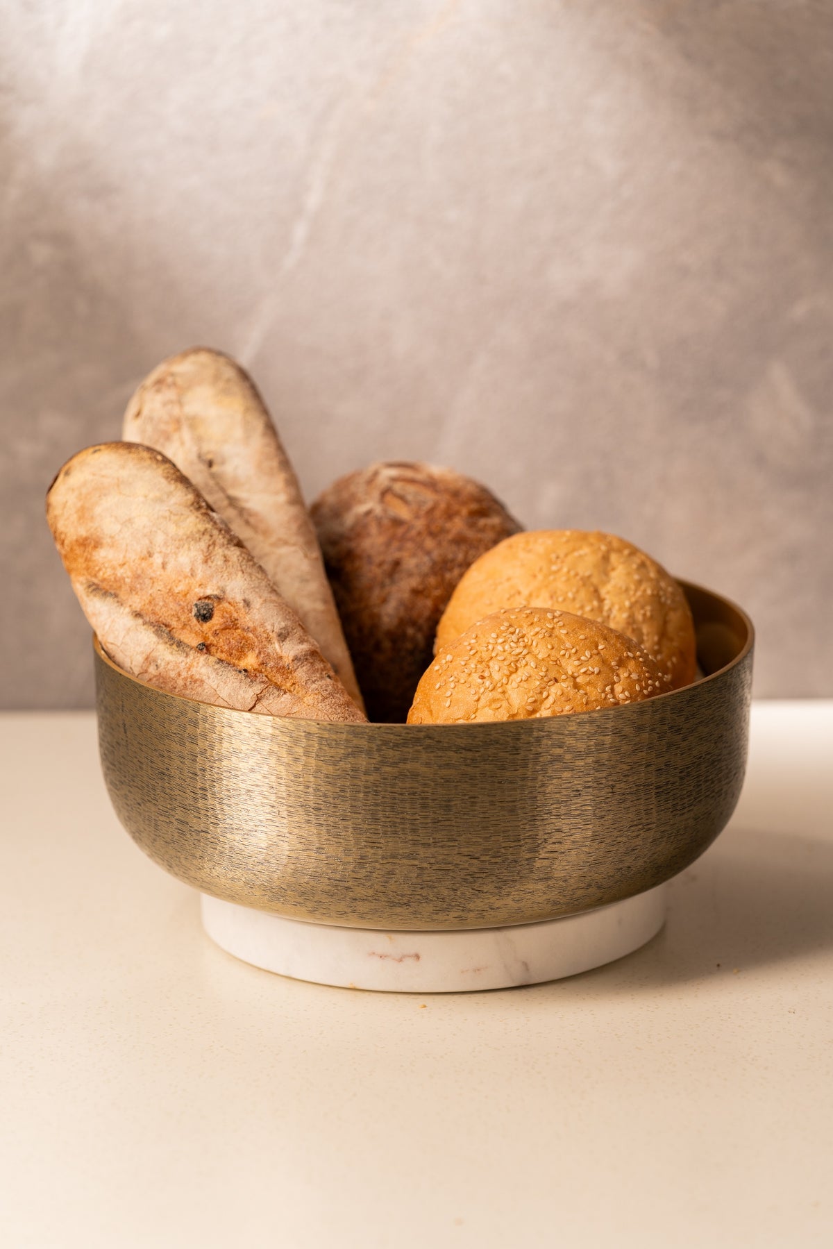 Hammered gold bowl with marble base filled with bread