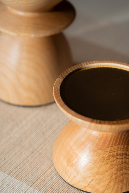 Two wooden pillar candle holders with lit pillar candles